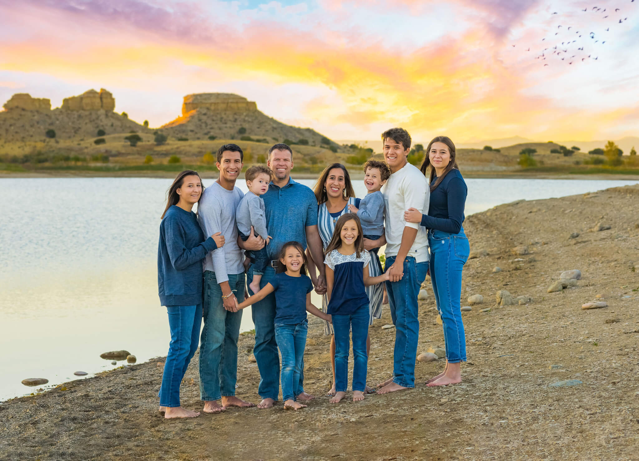 family of 10 standing on the beach of Pueblo Reservoir holding hands at sunset