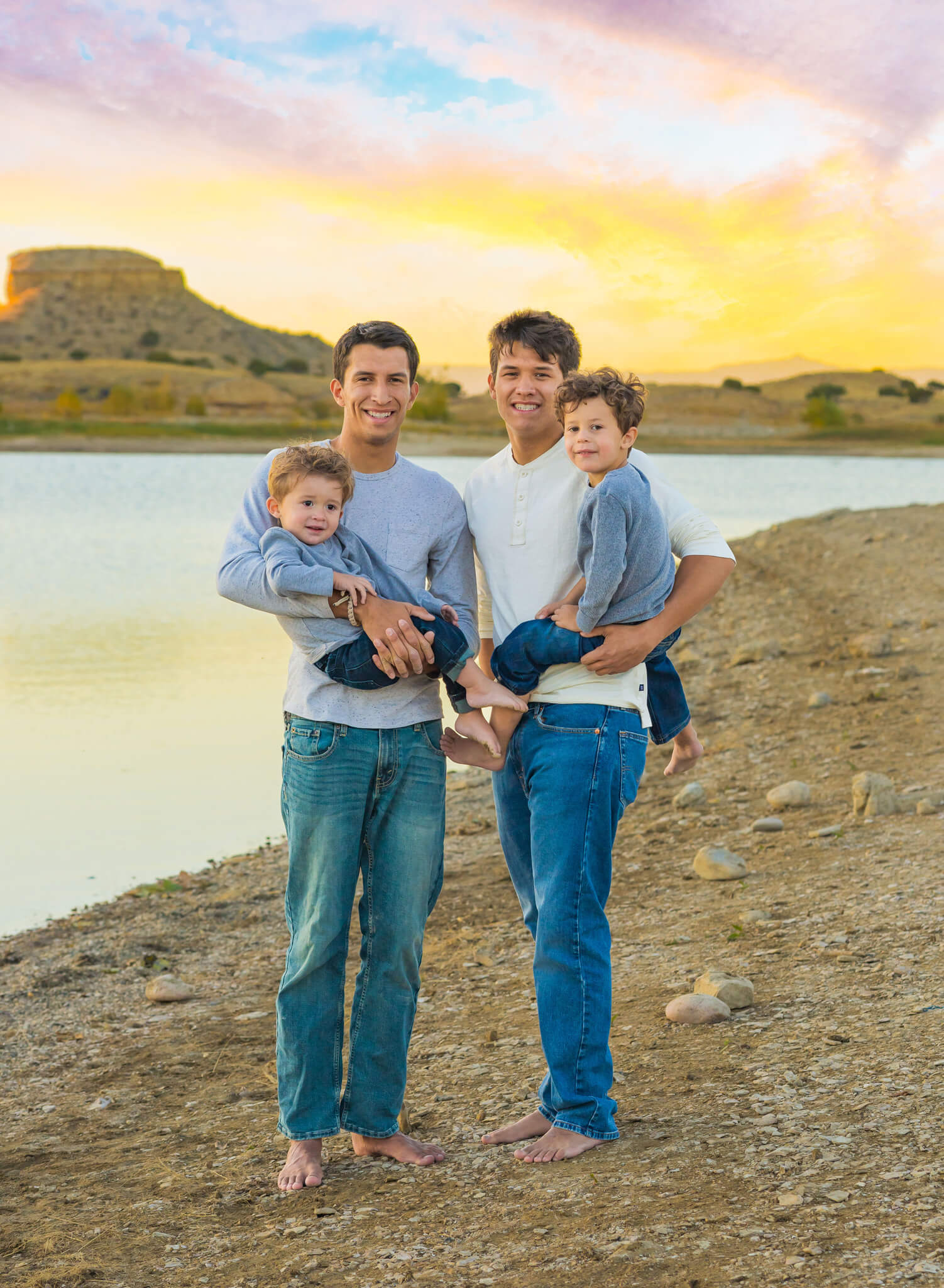 2 older brothers holding their 2 younger brothers standing on the beach at the Pueblo Reservoir at sunset