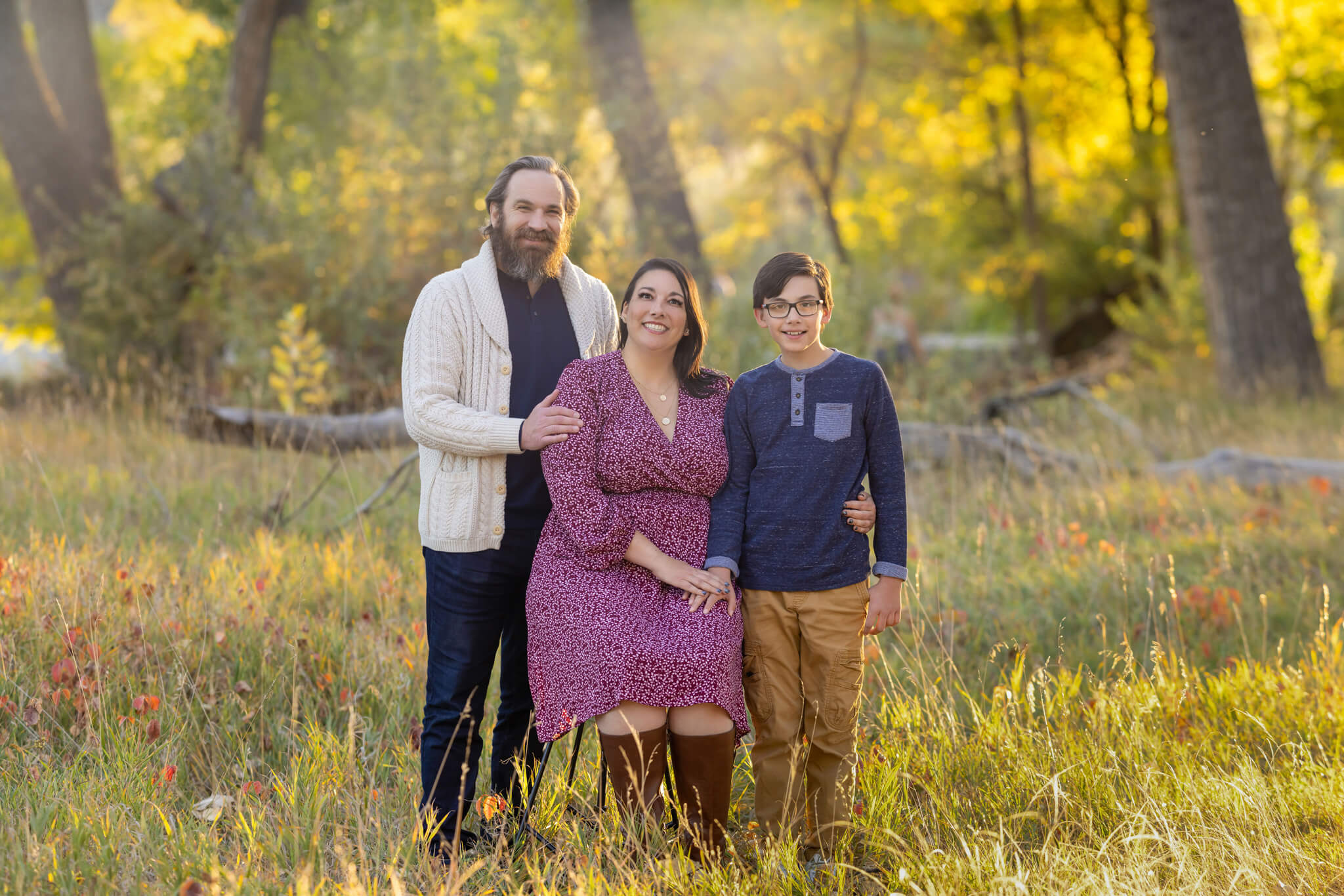 a mom, dad and young son standing together in fall colored grasses holding hands at City Park in Pueblo CO