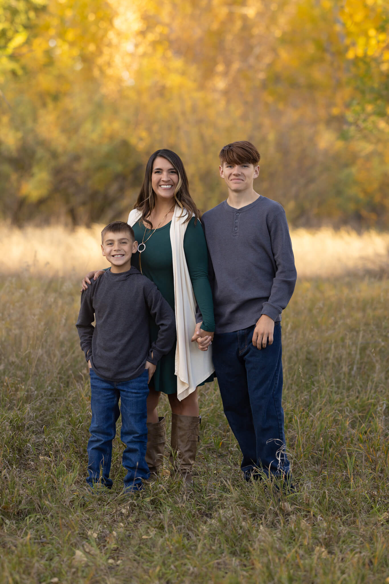 mom and her two sons standing next to each other holding hands in a field at City Park in Pueblo CO