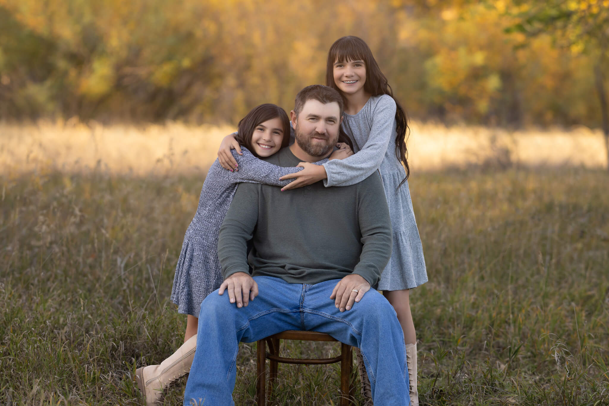 a dad and his two daughters hugging each other a field at City Park in Pueblo CO