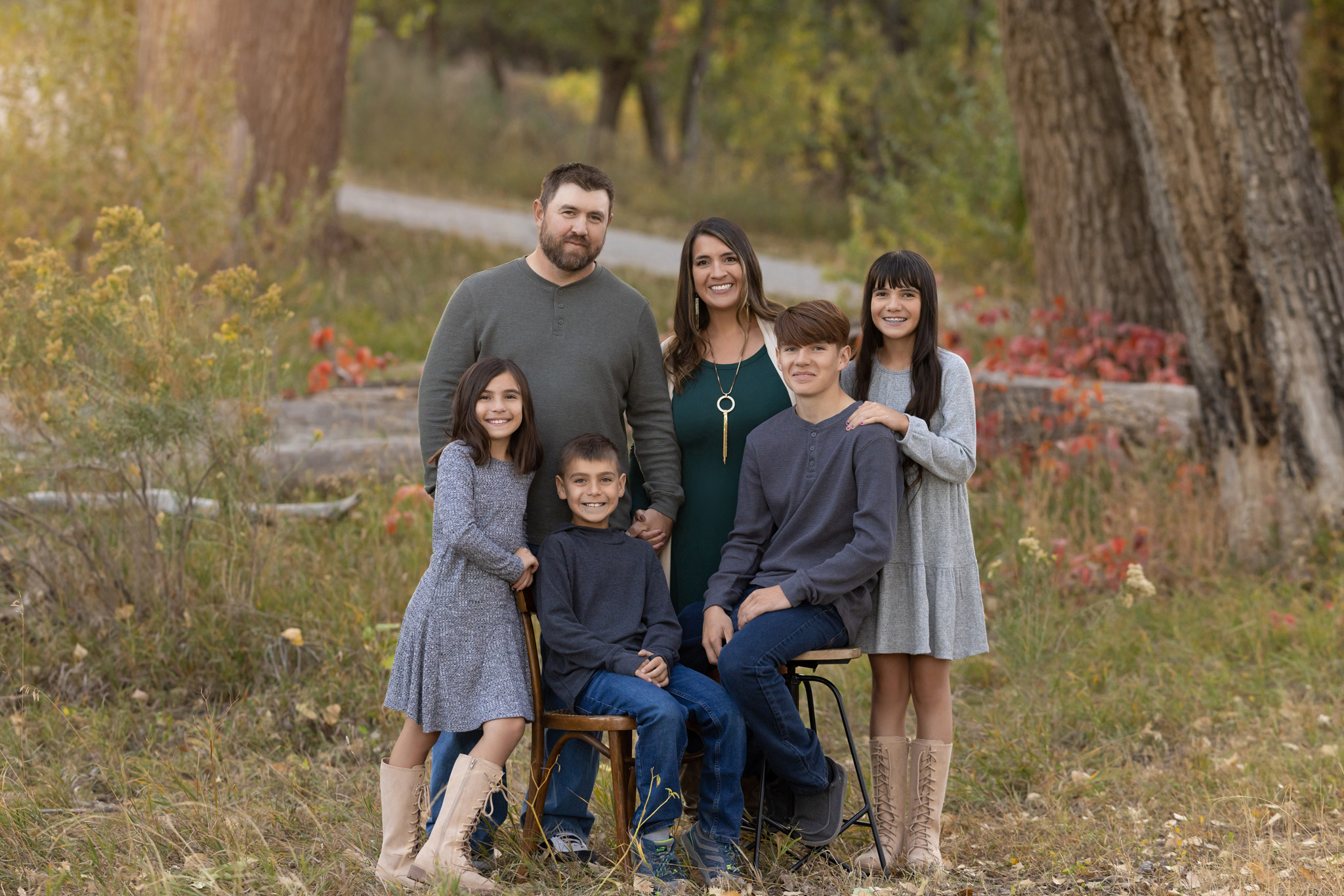 a family of 6 standing and sitting close together in a field in City Park in Pueblo